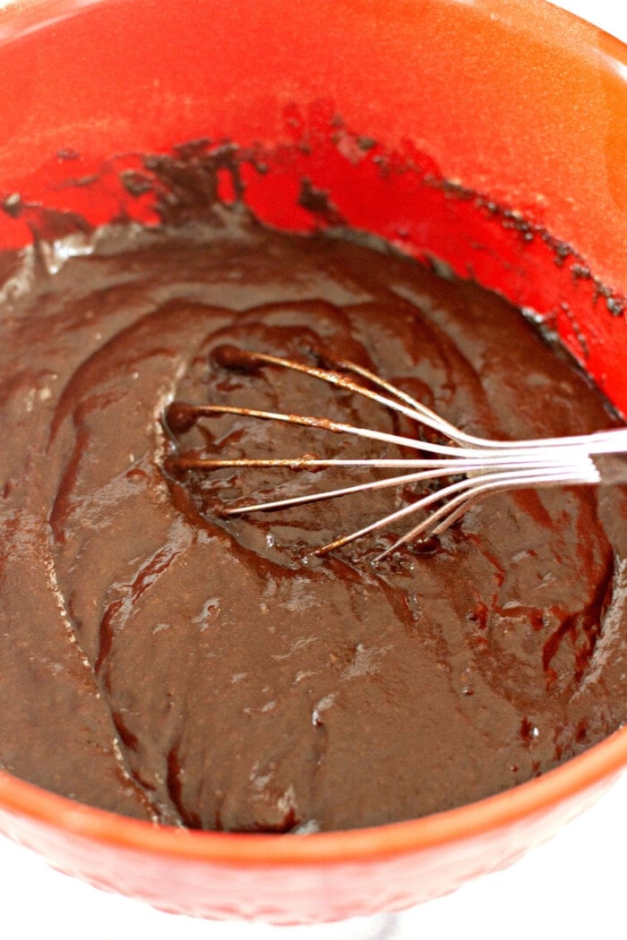 A whisk mixing chocolate cupcake ingredients