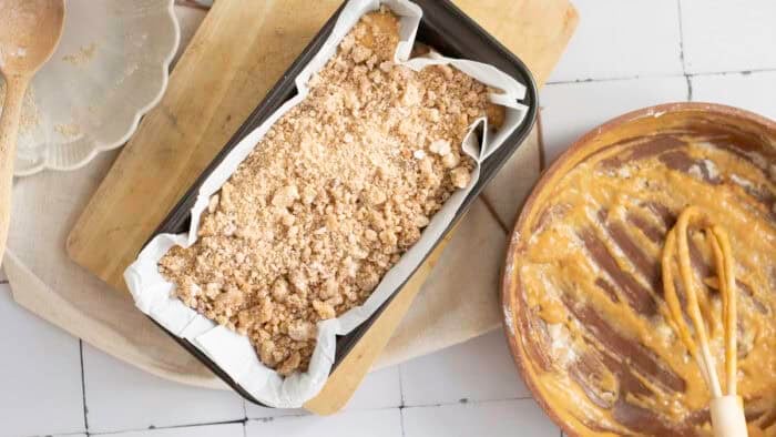 Streusel topping on top of pumpkin bread batter in a pan