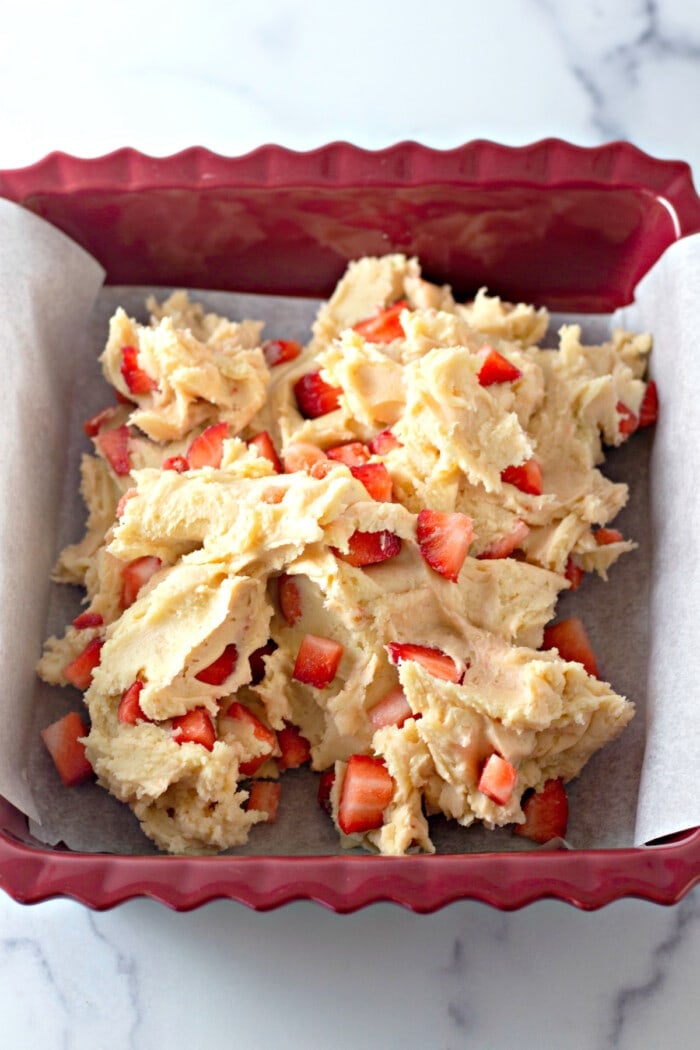 Strawberry lemon blondie batter added to a red silicone baking pan lined with parchment paper.