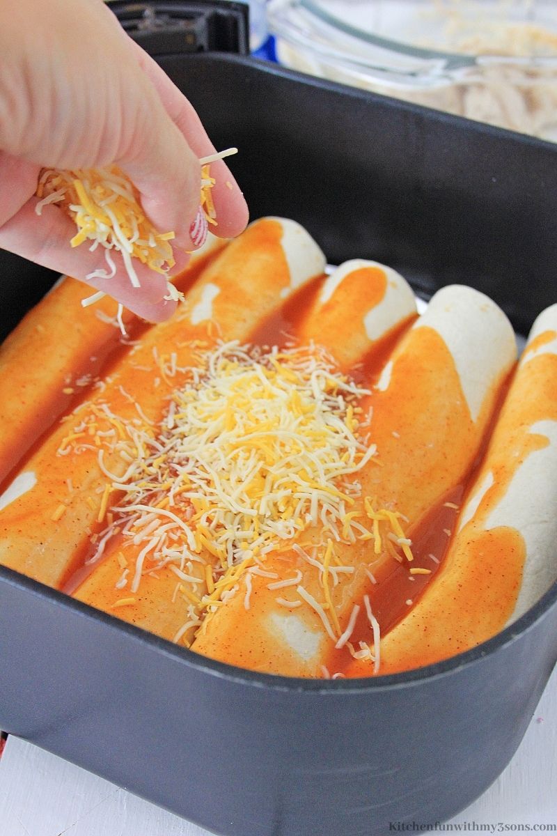 Enchiladas with sauce and cheese sprinkle on top in a pan.