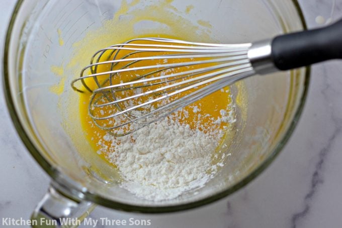 whisking together the ingredients to make pastry cream in a clear batter bowl