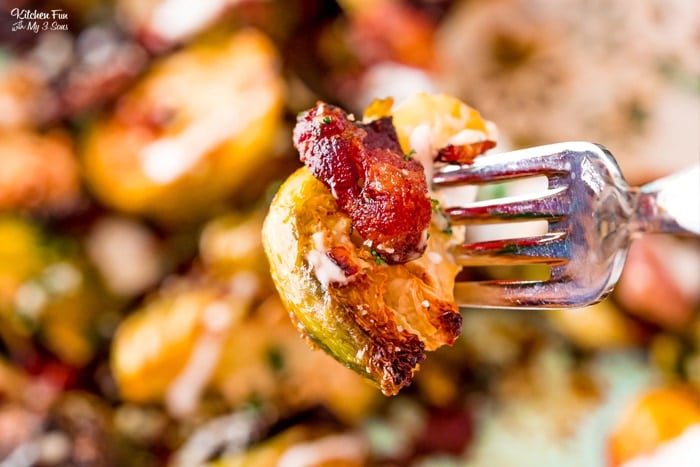Close up of a roasted Brussels sprout on a fork with a piece of bacon.