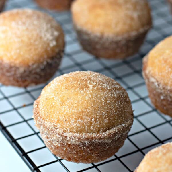 Nine donut muffins lined up on a wire rack on top of a kitchen counter