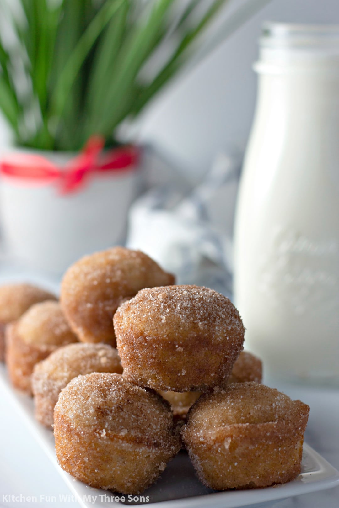Cinnamon sugar muffins piled onto a plate with a glass of milk in the background