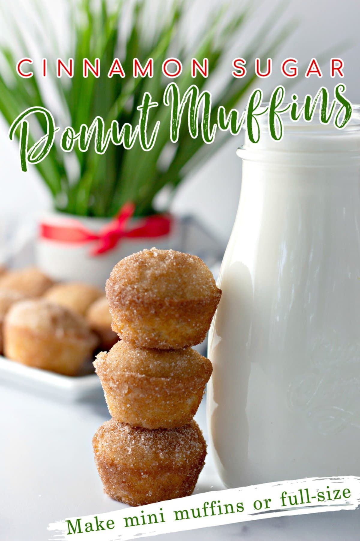 Three cinnamon sugar donut muffins stacked on top of each other beside a cold glass of milk with a plant in the background