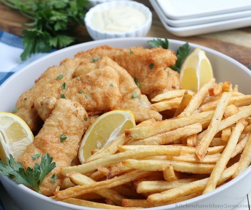 The Classic Fish and Chips Recipe garnished with cilantro and lemon. 