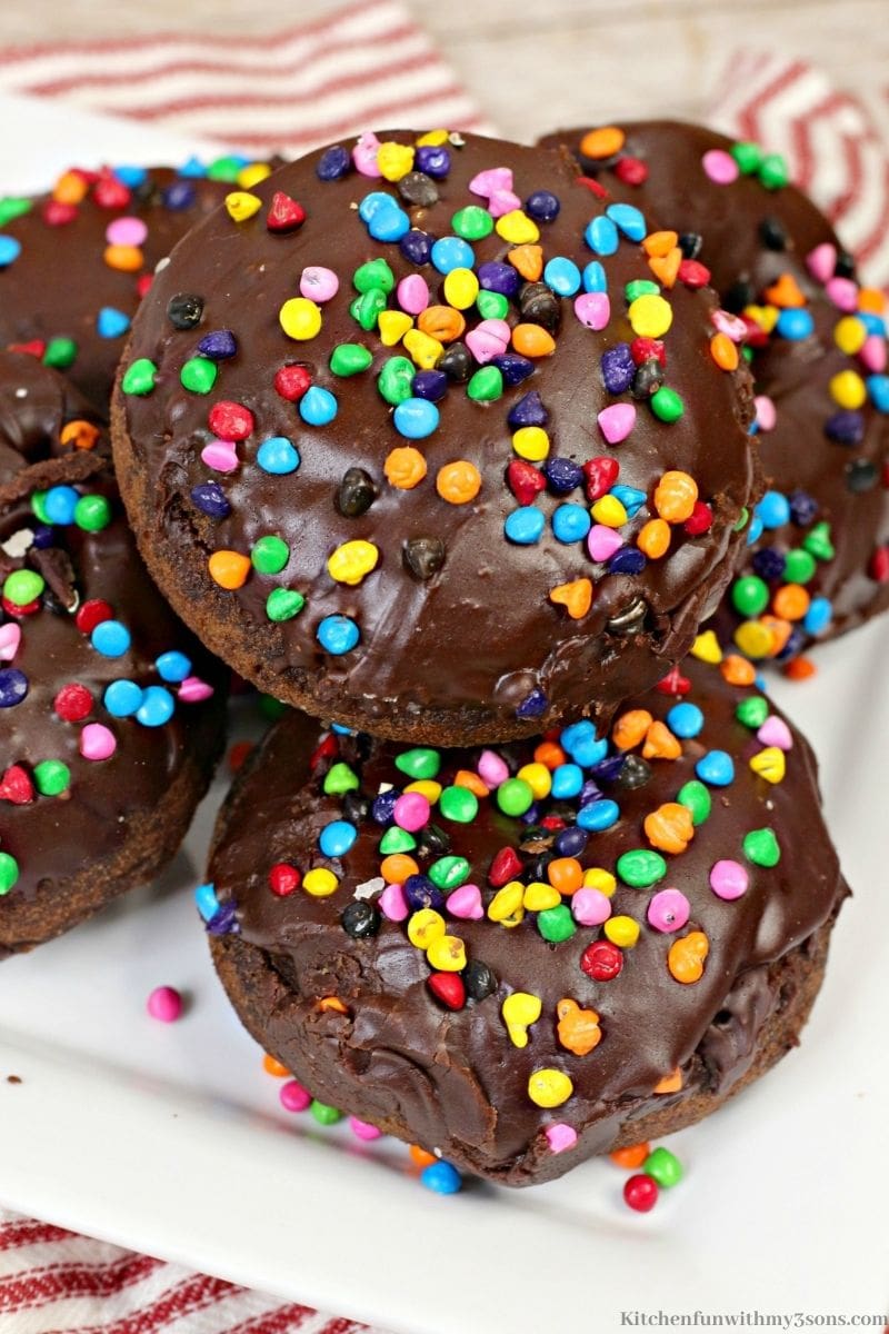 Close up image of the Cosmic Brownie Chocolate Donuts with sprinkles all around.
