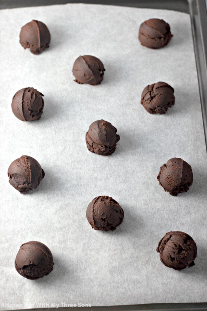 cookie dough balls on a parchment paper covered baking sheet