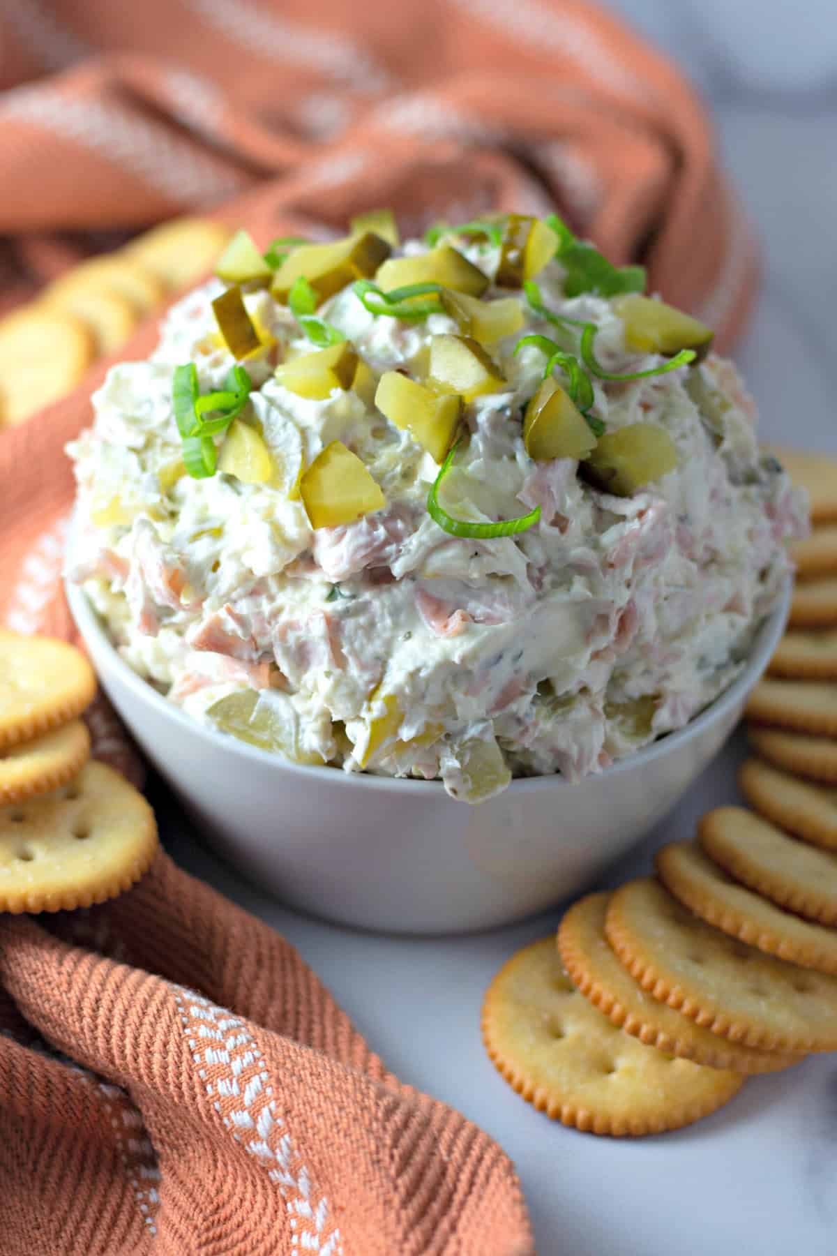 Made with chopped dill pickles and ranch seasoning, this Dill Pickle Dip recipe is ready in just 5 minutes. Perfect for parties! A bowl of dill pickle dip surrounded by crackers