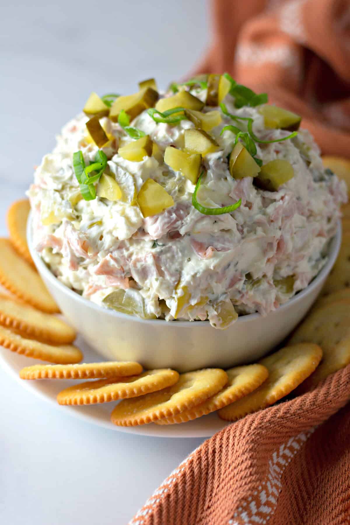 A bowl of dill pickle dip surrounded by crackers