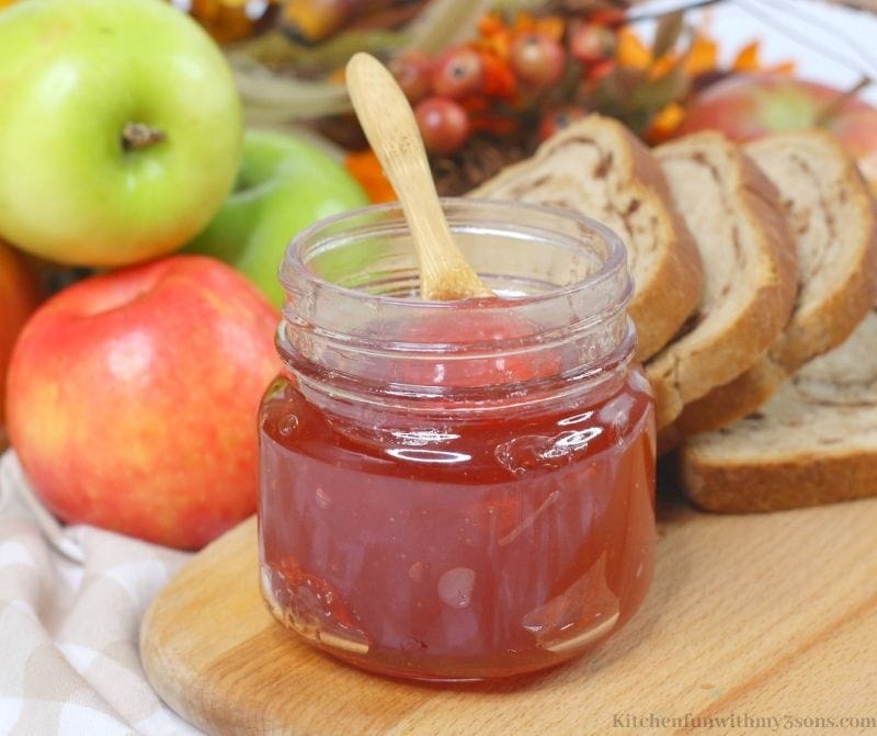 Close up view of the Instant Pot Apple Jelly with apples, twigs, and berries behind it.