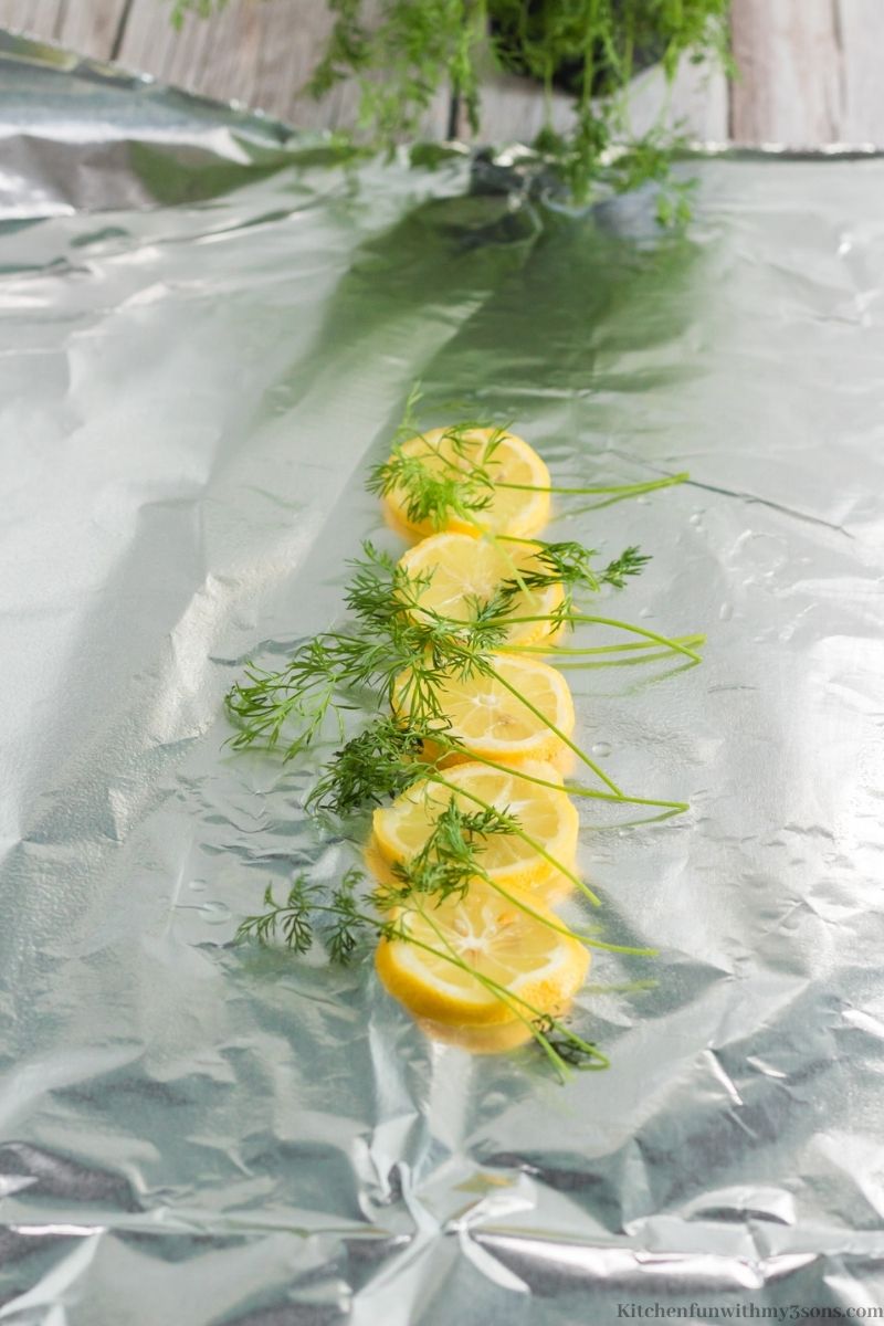 Lemons arranged on foil with dill on top.