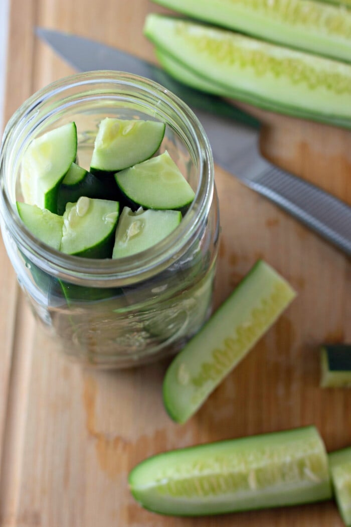adding cut cucumbers into jars