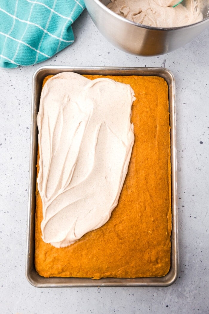Cream cheese frosting being spread over pumpkin bars