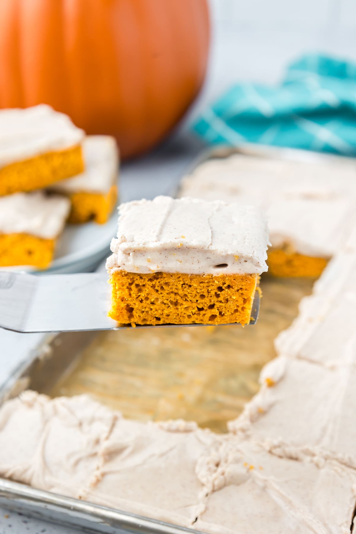 A spatula holding a pumpkin bar with cream cheese frosting