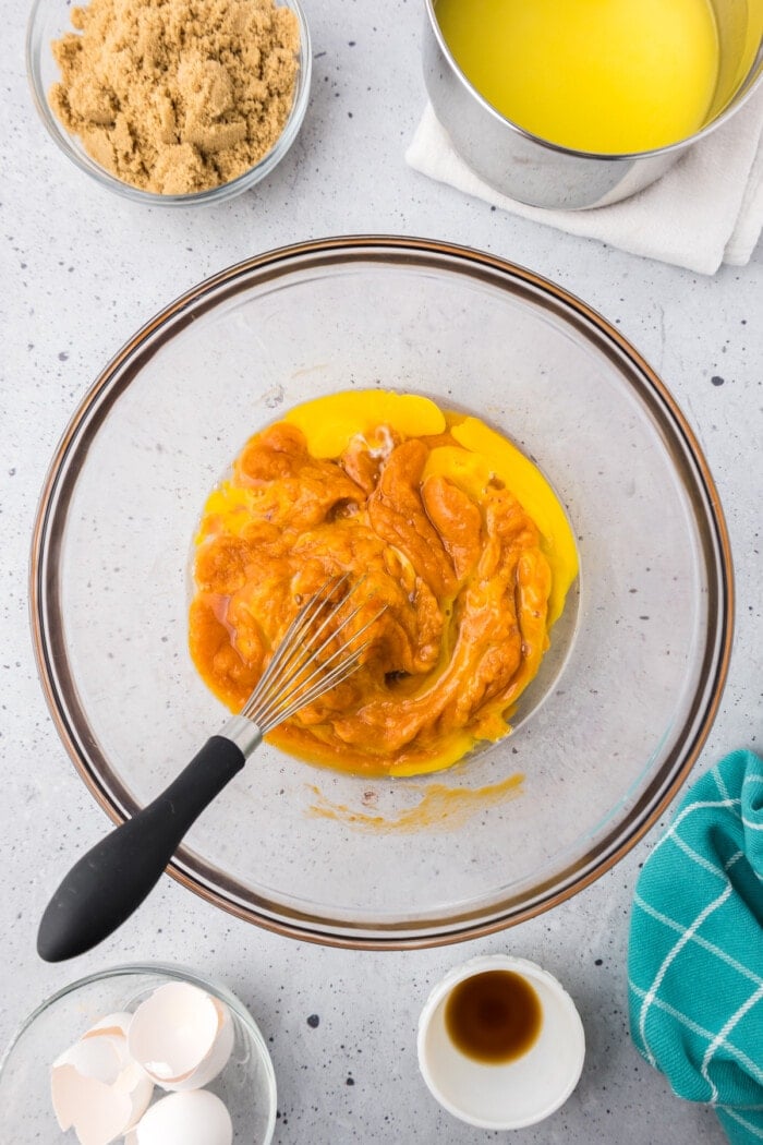 Pumpkin puree and eggs in a bowl with a whisk