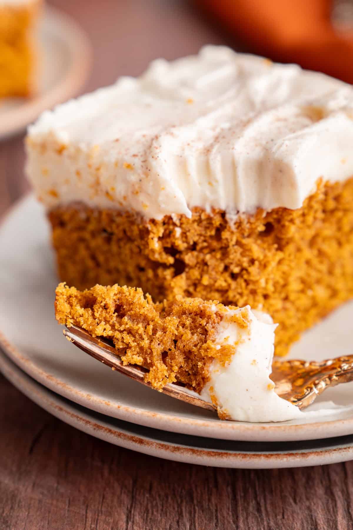 These Pumpkin Bars are soft, incredibly moist and loaded with warm spices. a bite taken out of a pumpkin bar with a fork.