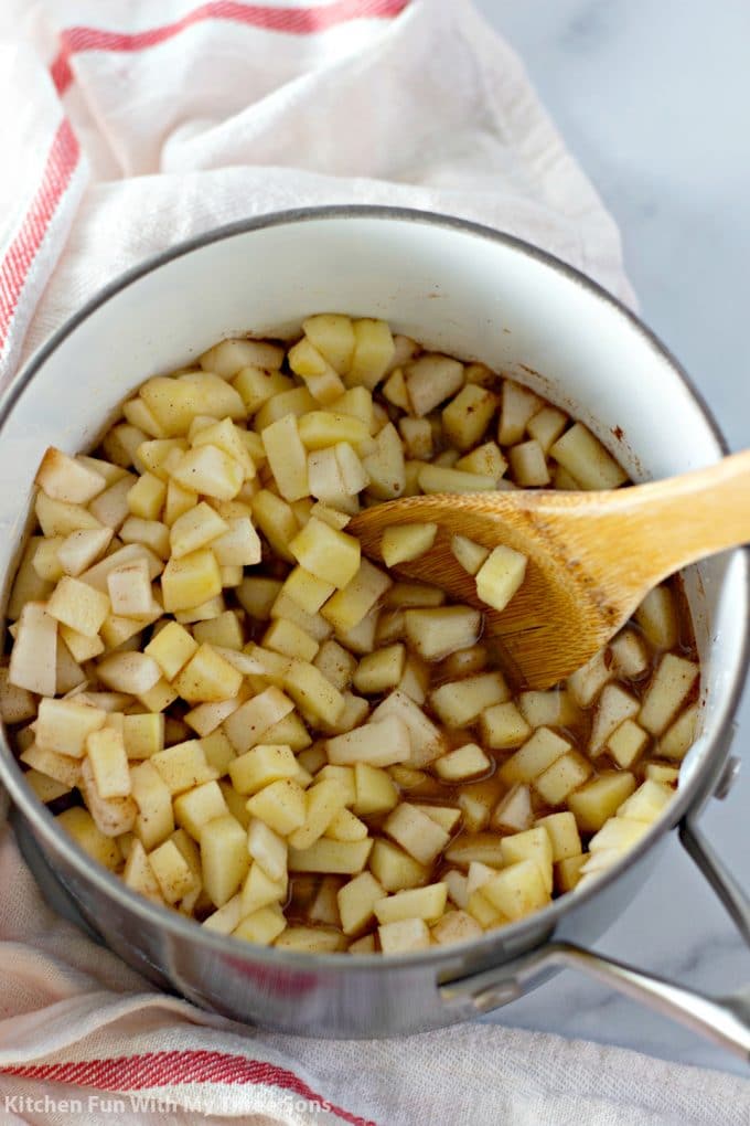 stirring apple chunks into cinnamon, sugar, and water in a saucepan
