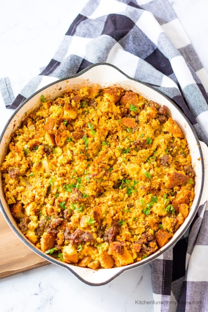 Best Ever Sausage Cornbread Stuffing on a wooden tray next to a patterned cloth.