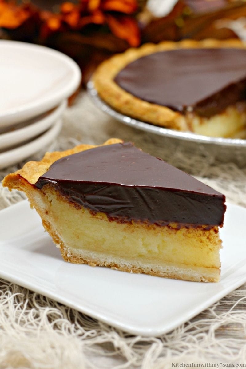 Close up of your Chocolate Buttermilk Pie with the whole pie behind it with extra serving plates.