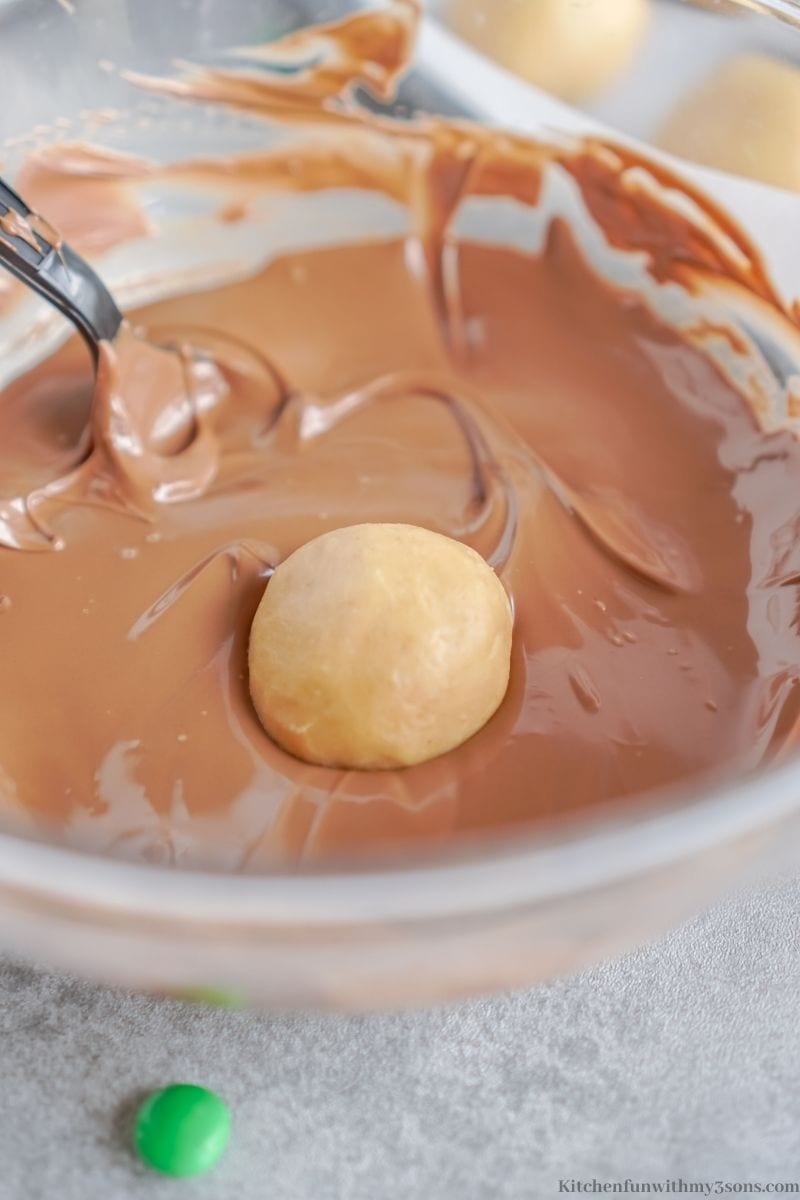 The dough being dipped into the melted chocolate.