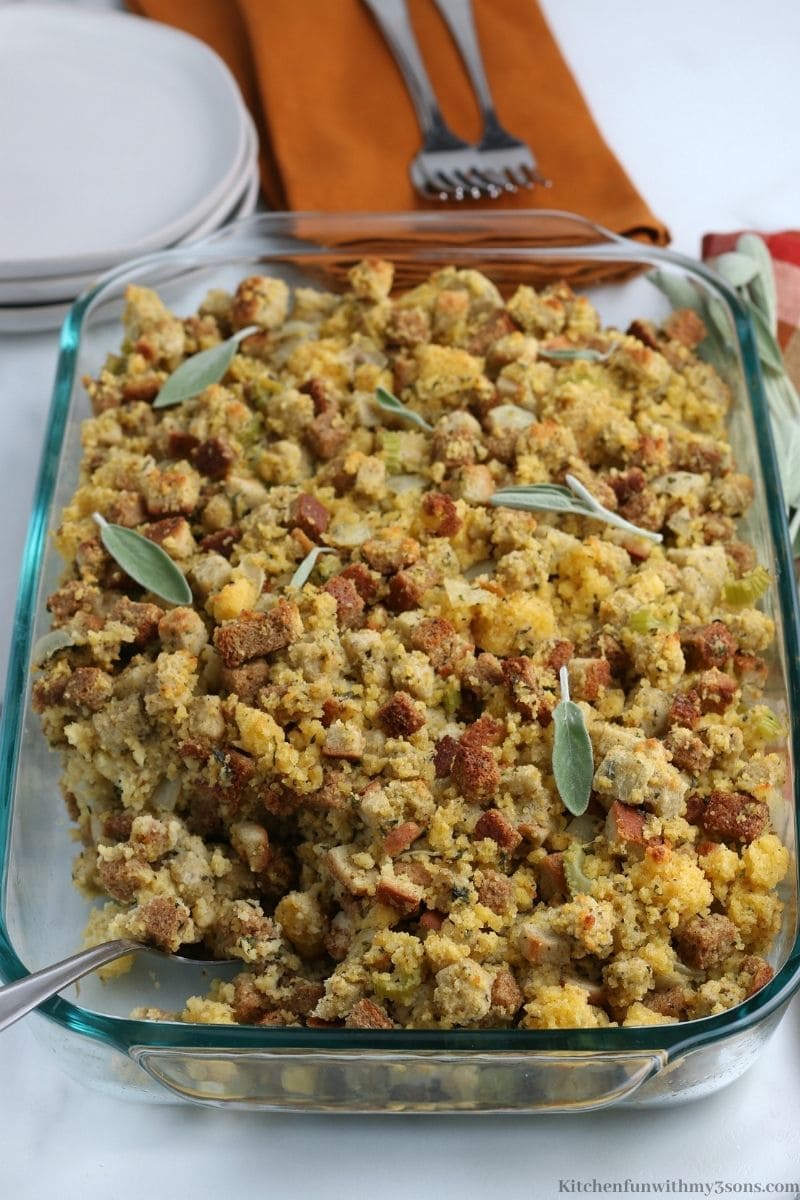 Cornbread Dressing Recipe with extra silverware and plates in the background.