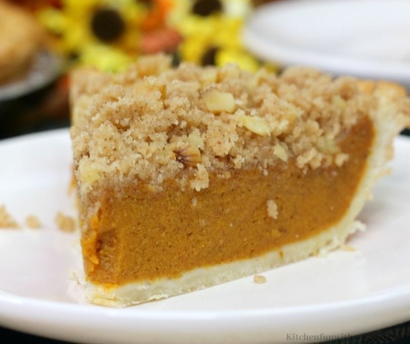 Walnut-studded crumble on top of a smooth pumpkin filling in a slice of pie.