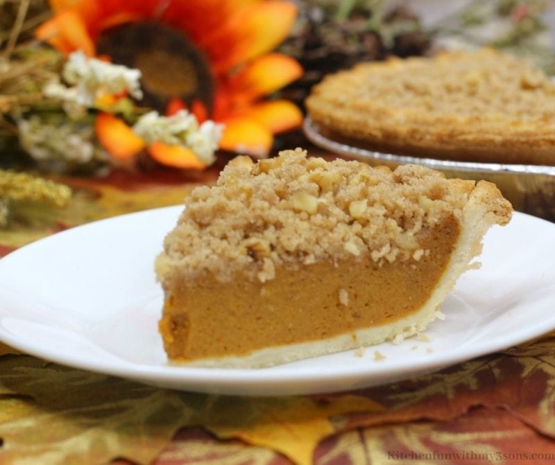 A slice of pumpkin pie with a crumbly layer of streusel on top.