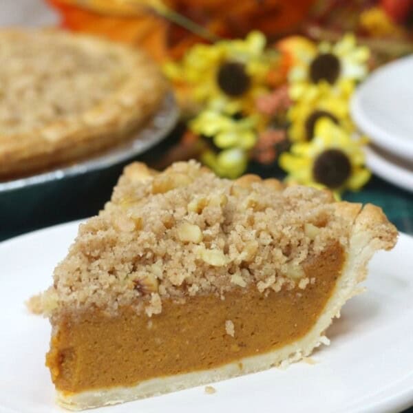 Pumpkin pie topped with a buttery crumble sitting on a plate.