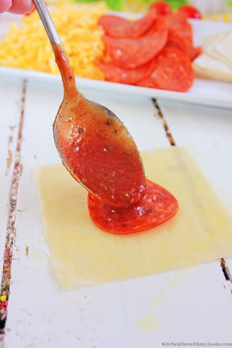 Adding sauce onto your pepperoni in the wonton.