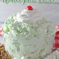 Title image for Easy Watergate Salad featuring Watergate salad in a clear bowl topped with whipped cream and a cherry.