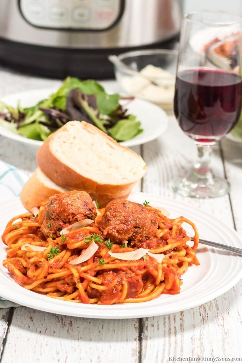 Homemade Spaghetti and Meatballs Recipe with a side salad and wine.