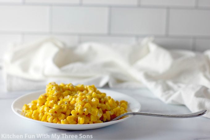 sweet yellow corn on a white plate with a fork