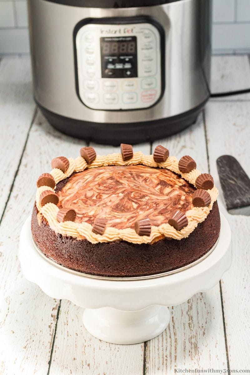 The whole Instant Pot Chocolate Peanut Butter Cheesecake on a serving stand.