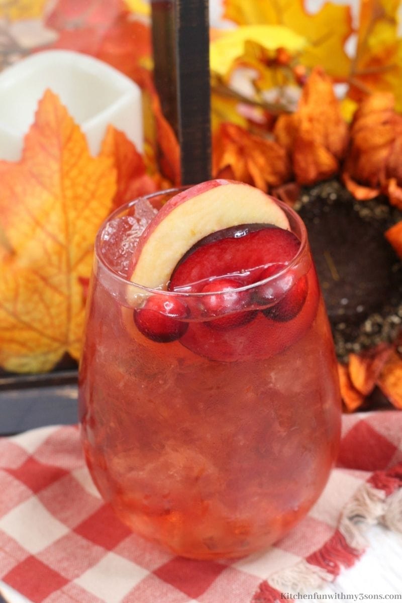 Plum Apple Hot Toddy Whiskey Drink with Fall decorations behind it.