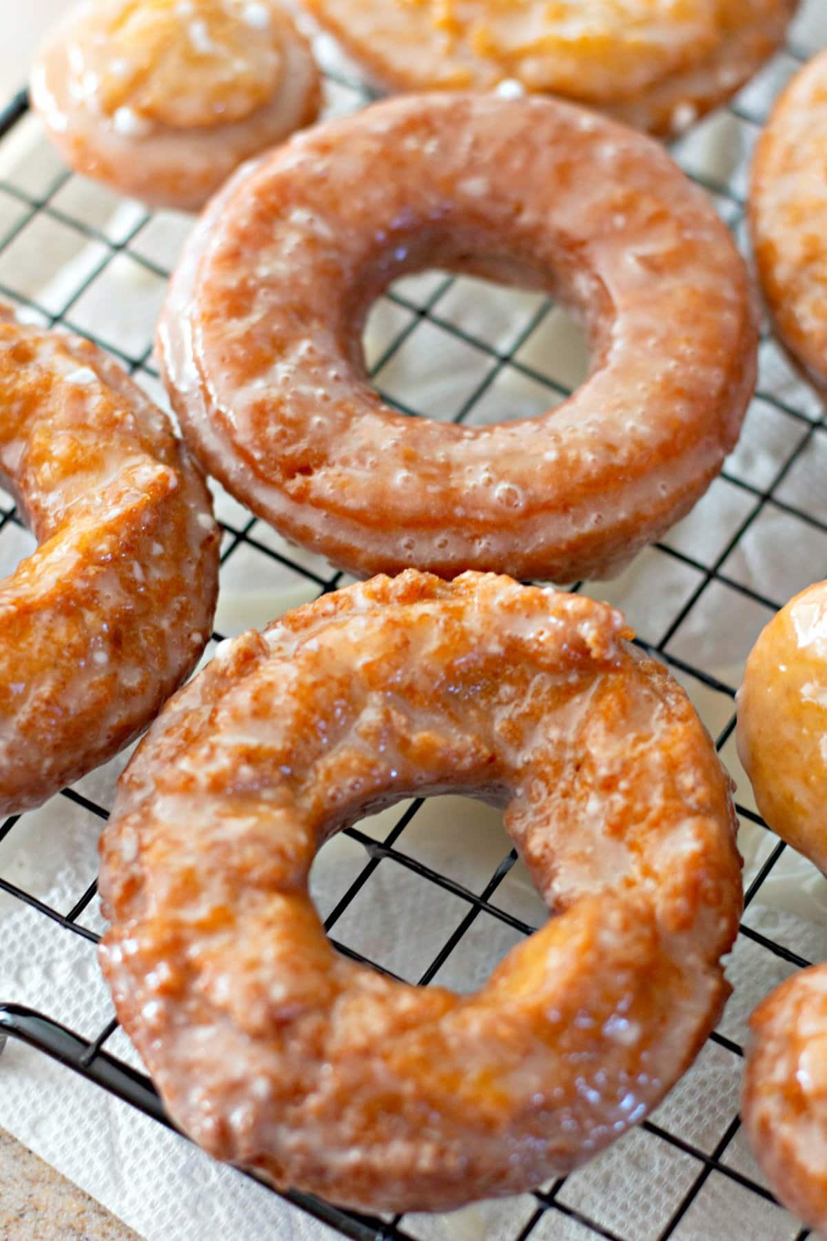 Close up of glazed pumpkin donuts on a wire rack.