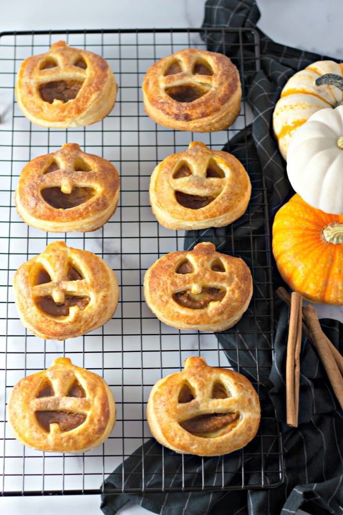 Easy Pumpkin Hand Pies on a wire cooling rack with a black towel and pumpkins