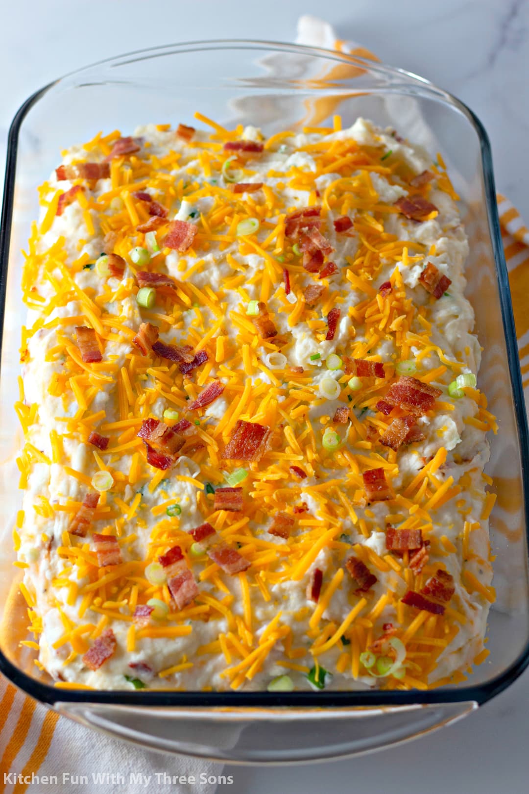 Mashed potatoes topped with cheese and bacon in a glass baking dish