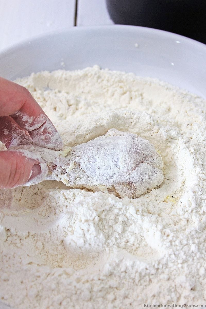 The egg and milk coated wing being placed in flour to coat.