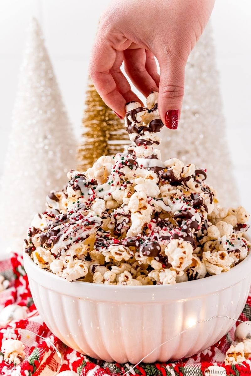  A hand lifting up Peppermint bark popcorn.