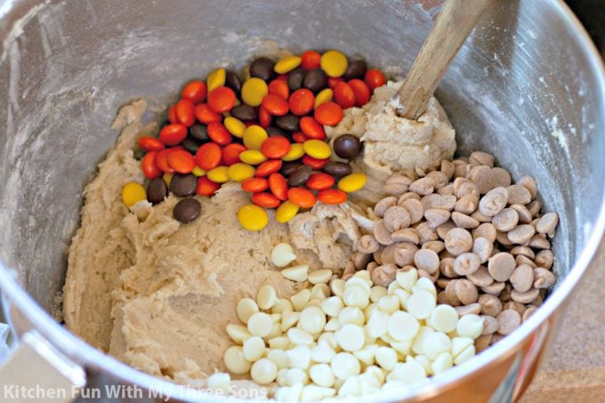 folding Reese's Pieces, peanut butter chips, and white chocolate chips into cookie dough