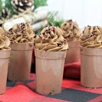 A close-up shot of five chocolate pudding shots topped with chocolate whipped cream