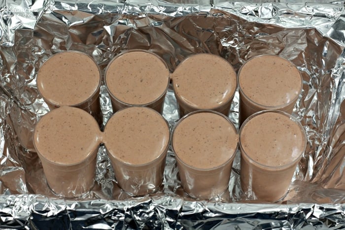 Eight un-chilled spiced mocha pudding shots inside of a bin lined with tin foil