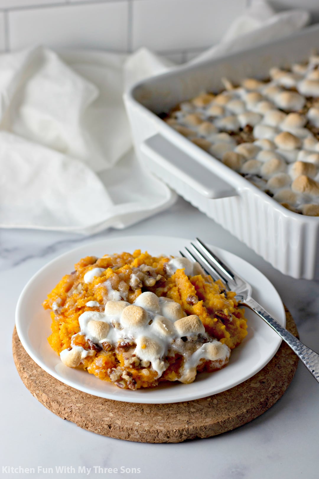 Sweet Potato Casserole with Pecan Streusel and Marshmallows on a white plate with a fork