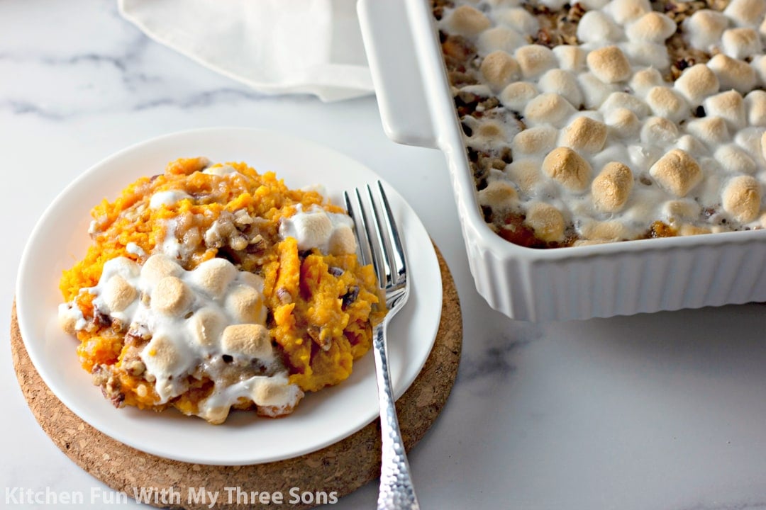 Sweet Potato Casserole with Pecan Streusel and Marshmallows on a plate next to a baking dish