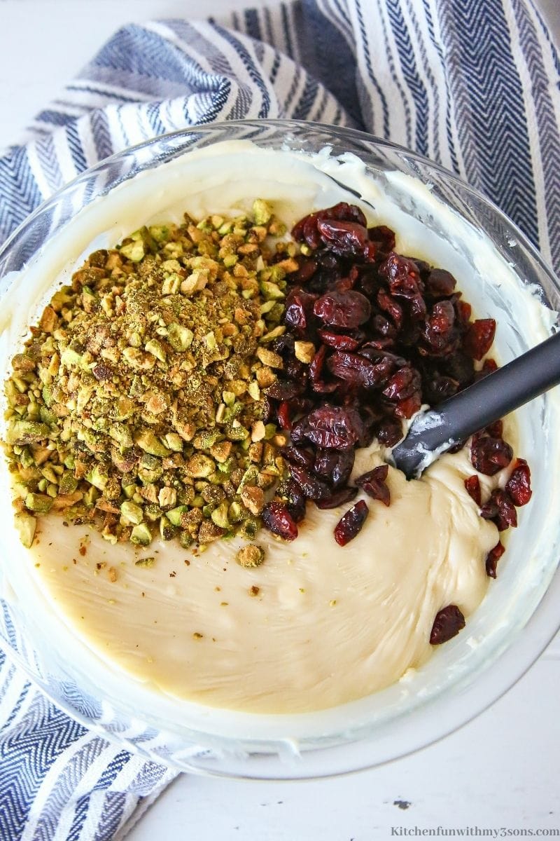 Adding the pistachios and cranberries into the melted chocolate.