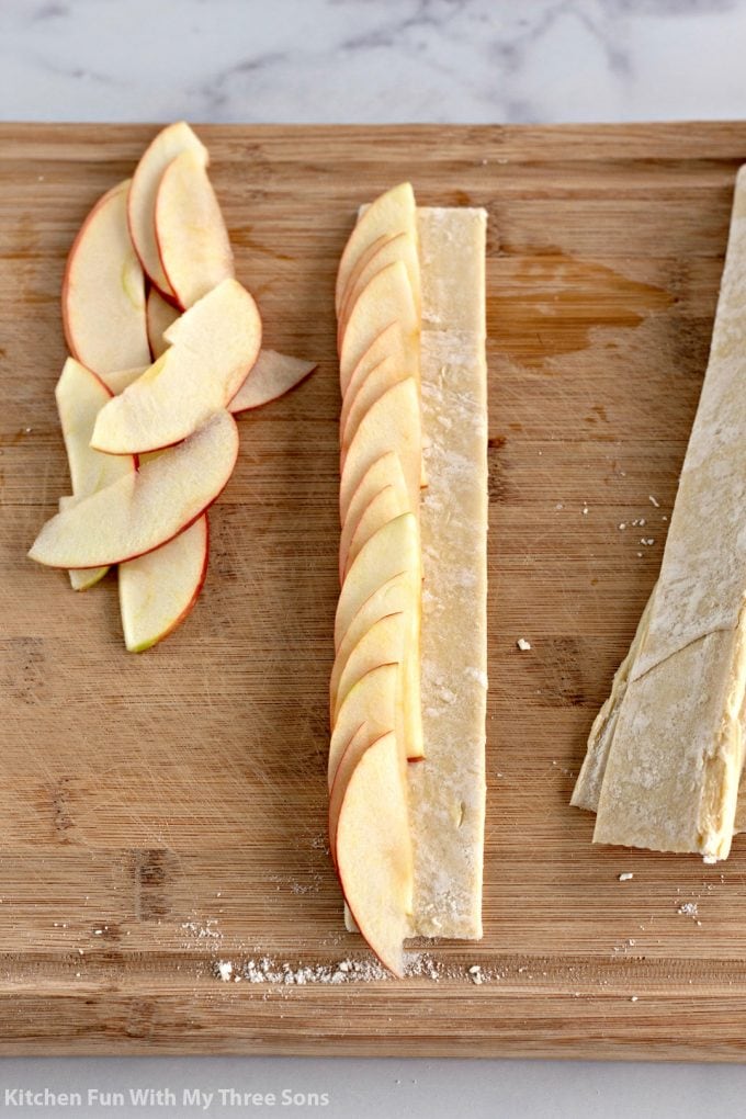 topping the strips of puff pastry with apples