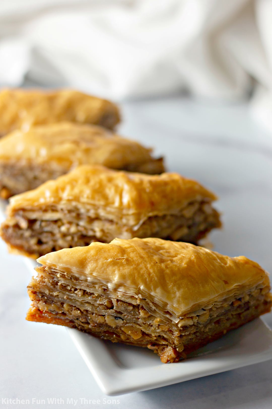 Close-up shot of baklava from the side, showcasing the layers of phyllo pastry and walnut filling.
