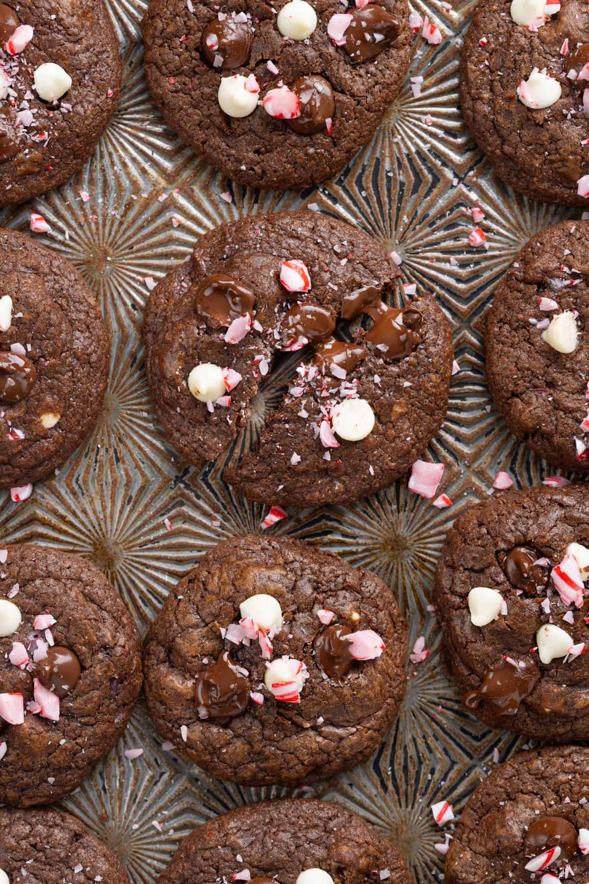 These Chocolate Peppermint Cookies are loaded with semi-sweet, white, and dark chocolate plus crushed peppermint. Soft & chewy! Overhead view of chocolate peppermint cookies on a baking sheet