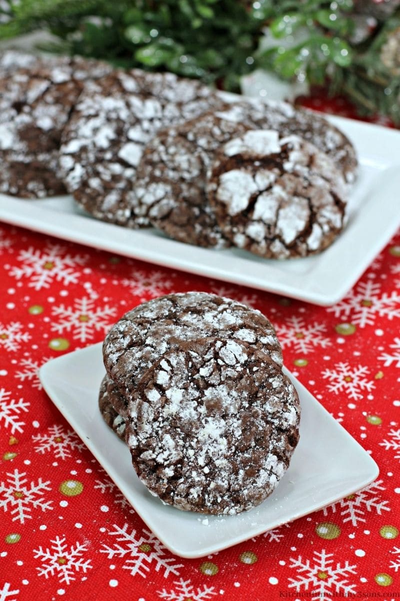 Chocolate Rum Crinkle Cookies on a plate with more behind them on a serving platter.